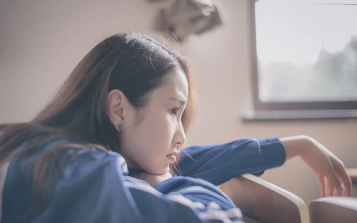 一名女子靠在窗边，柔和光线映照着她的侧脸。