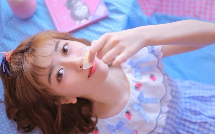 一名成年女性躺在藍色格紋墊子上，手持一小片食物靠近嘴邊。