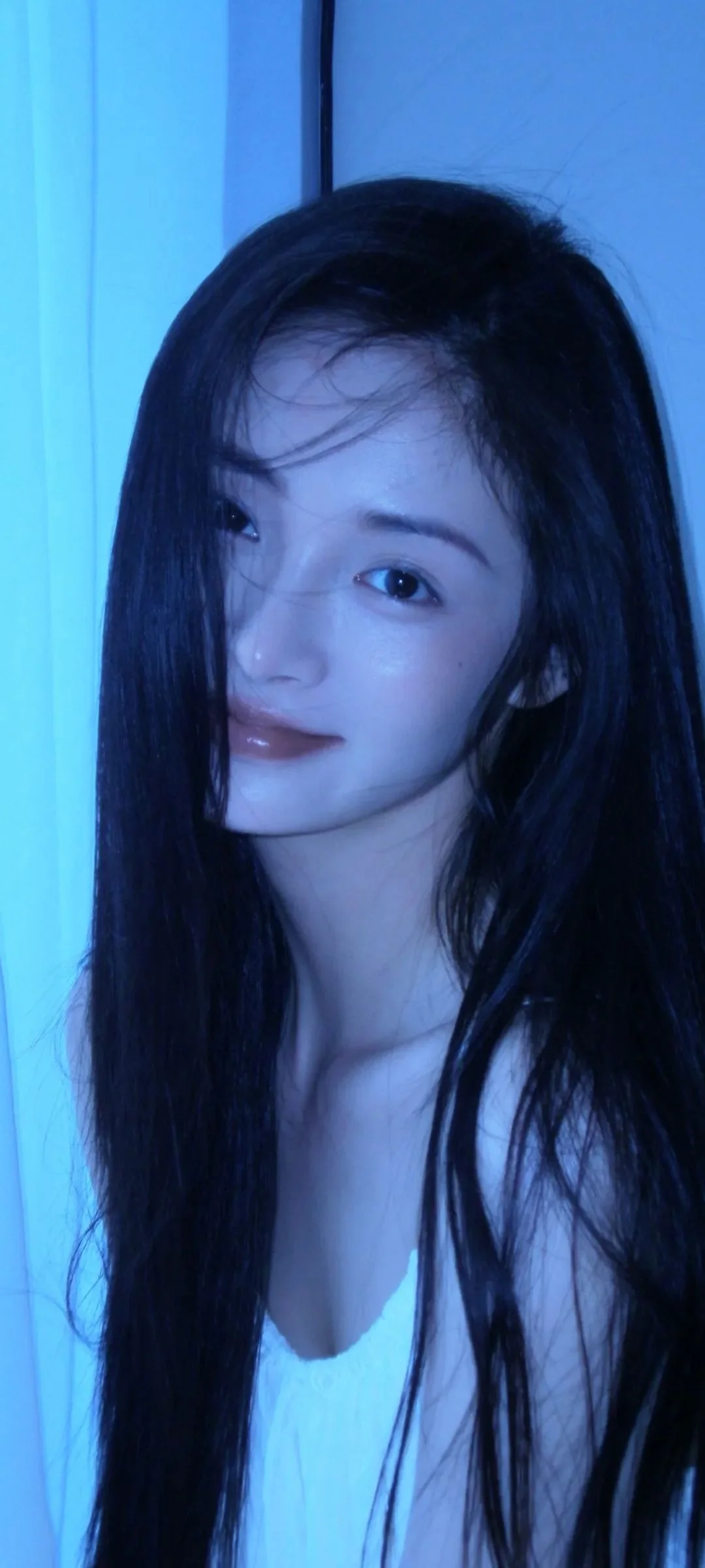 一位长发女性在蓝色光影中面对镜头，构成竖幅近距离人像。