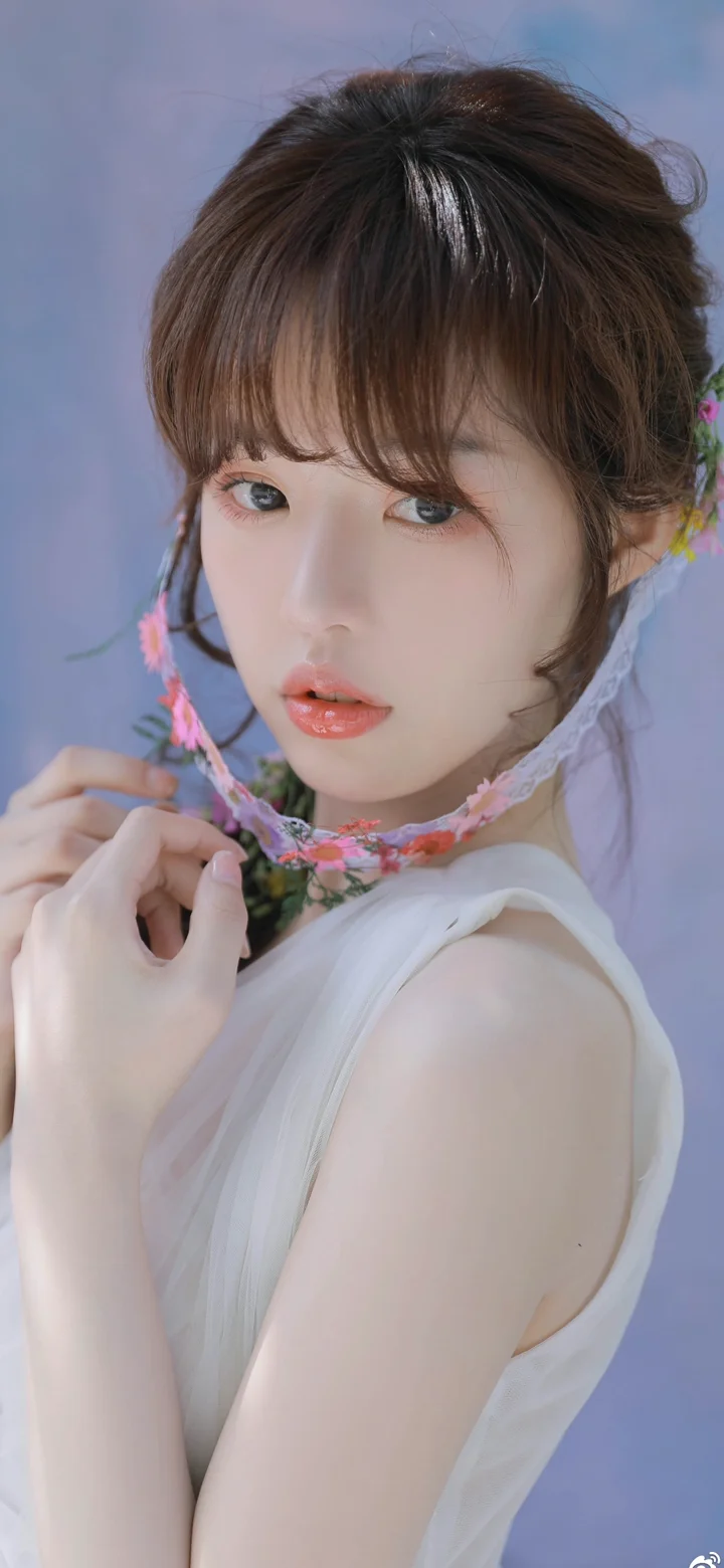 一位成年女性佩戴花环项链，在浅紫色背景前注视镜头。