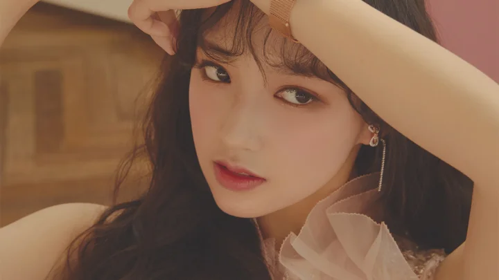 一名长发女性以手臂遮挡额头，面向镜头呈现暖色调近距离肖像。