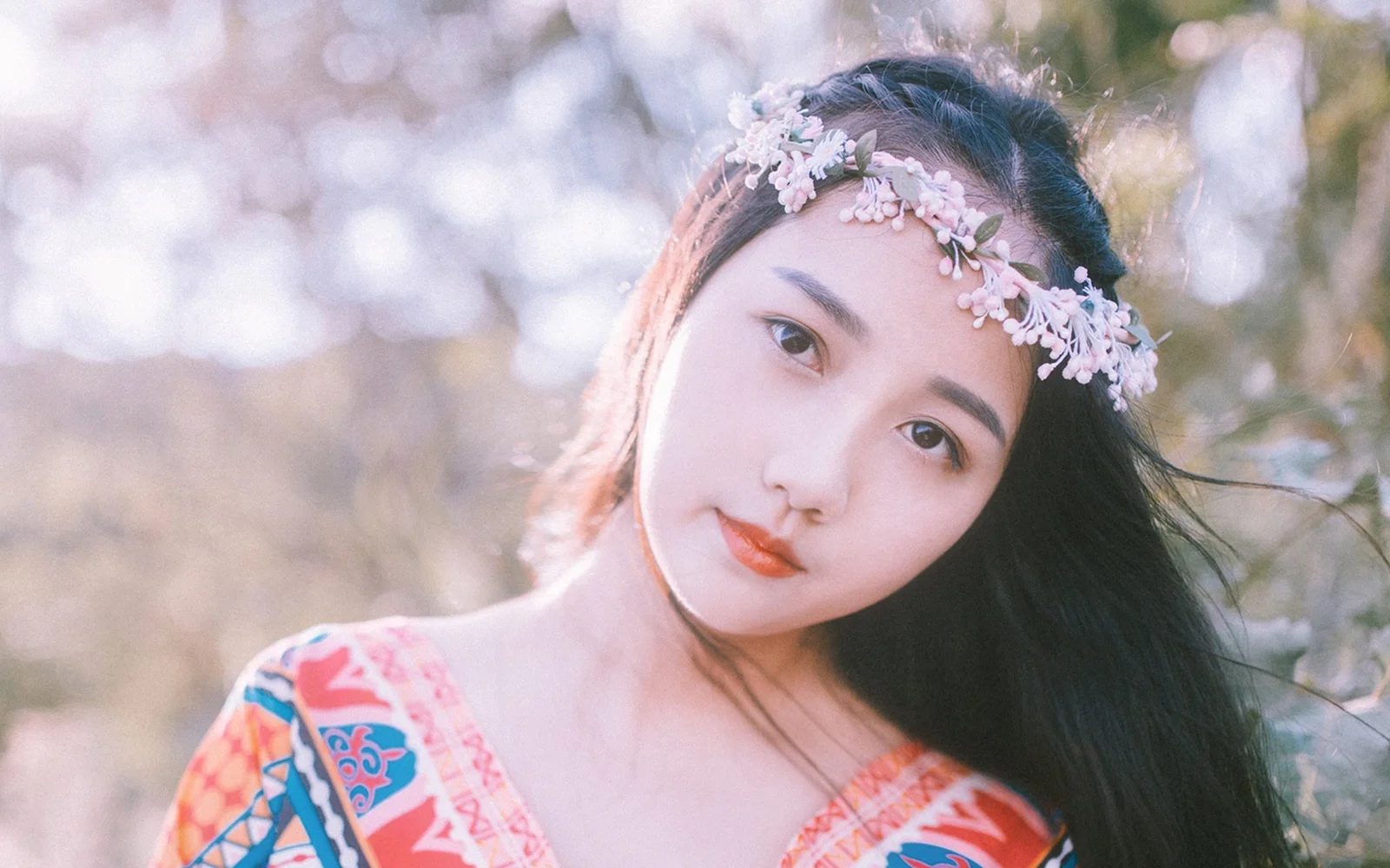 一位戴着花冠的成年女性在柔和的户外光线下望向镜头。