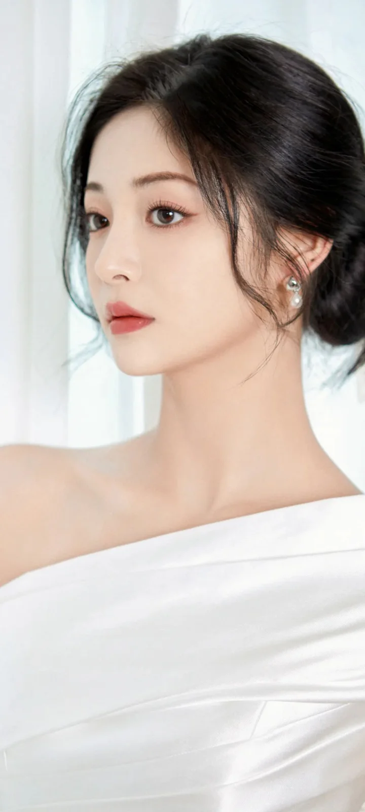 흰색 오프숄더 의상을 입은 성인 여성이 옆모습으로 카메라를 바라보고 있습니다.