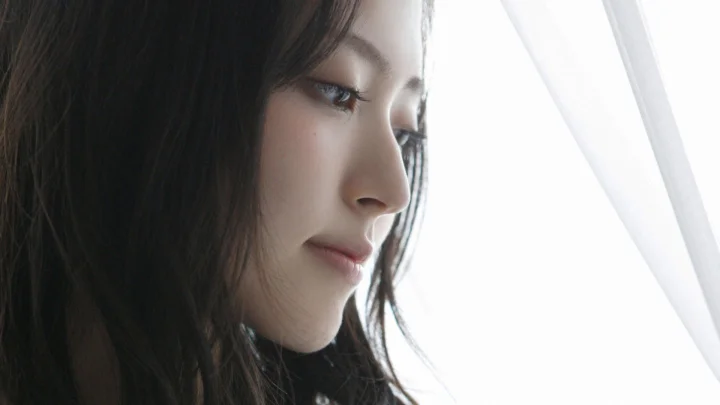 밝은 창가에서 성인 여성이 옆모습을 보이고 있다.