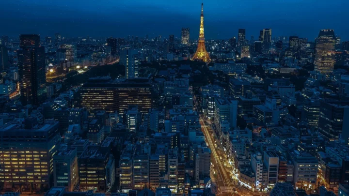 夜幕下的城市天际线被蓝色灯光笼罩，中央矗立着一座明亮的塔楼。