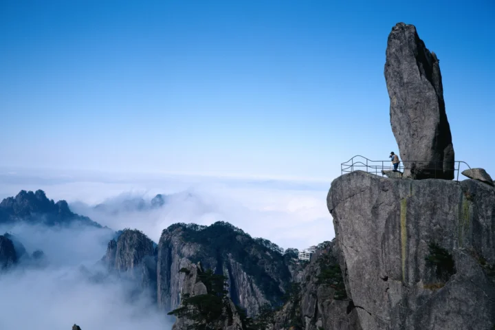 蓝天下，云雾缭绕的群山与突兀的巨石峰构成壮丽的自然景观。