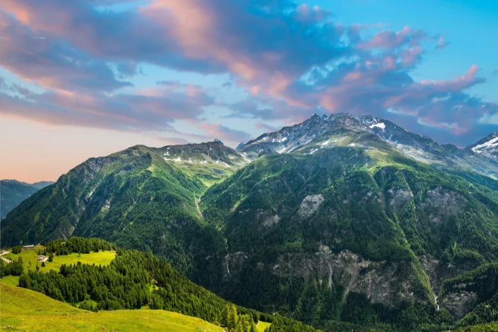 群山、森林和绿色山坡沐浴在彩霞映照下的自然风景。