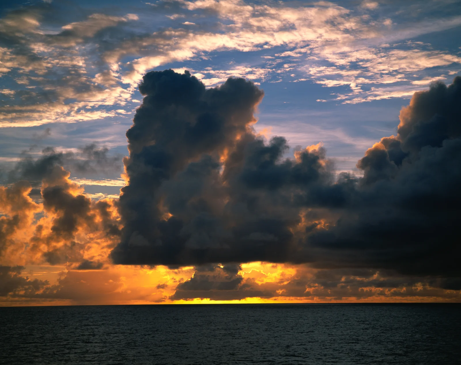 绚丽的夕阳照亮海面上层叠的乌云与云霞。