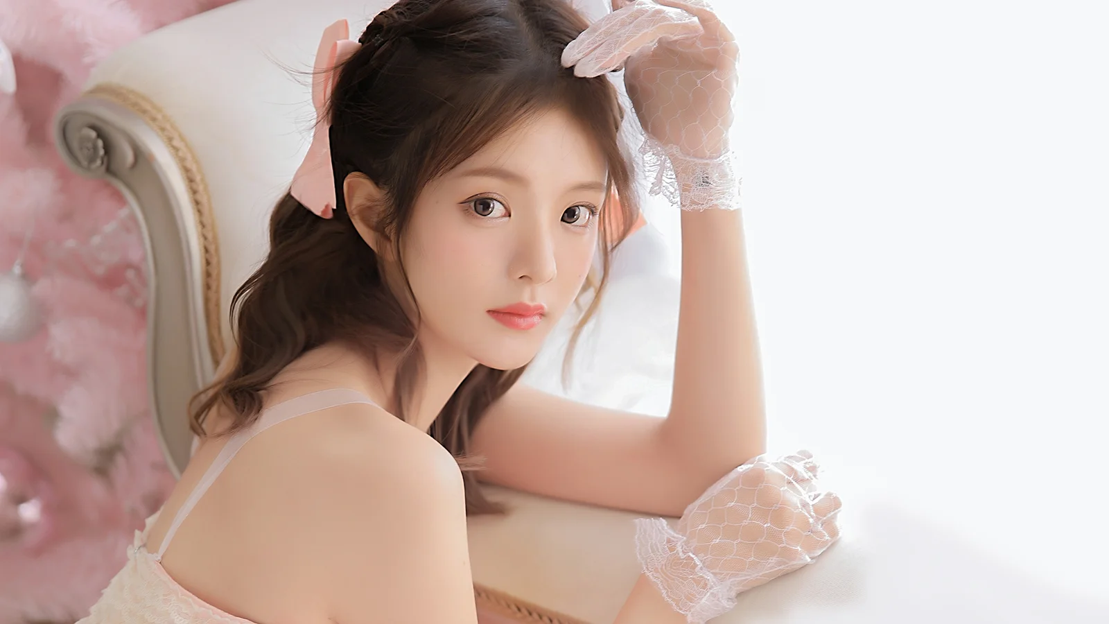흰색 레이스 장갑을 낀 여성이 밝은 창가에서 카메라를 바라보고 있다.