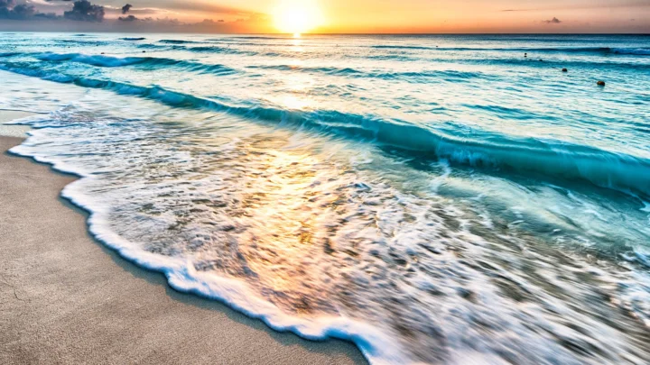夕阳照耀着海滩与层层涌来的海浪。