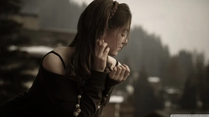 一名身穿深色衣服的女性面向光线，身后是柔焦的城市背景。