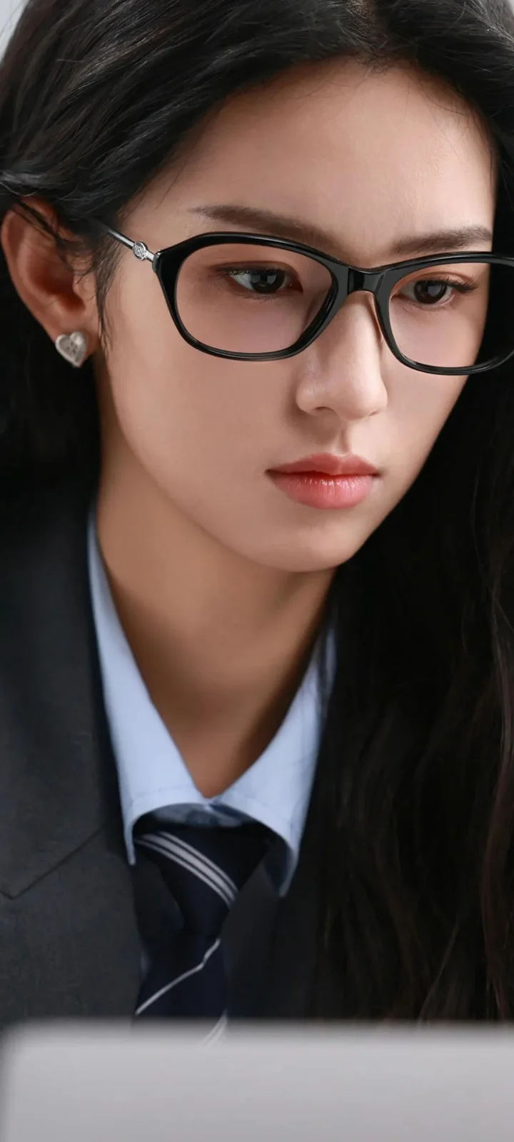一位戴黑框眼镜、穿深色西装和衬衫的女性近距离肖像。