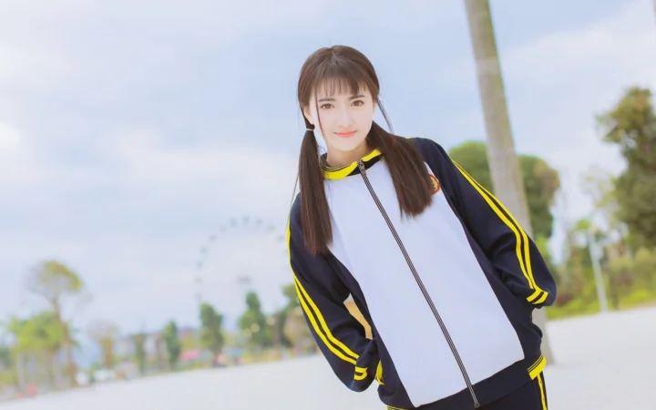 一名身穿黑黄运动服的成年女性站在户外道路旁。