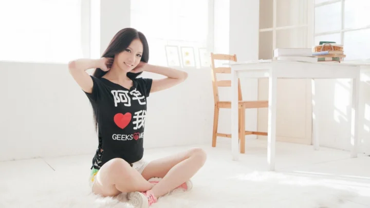 一名成年女性坐在明亮的白色室内地面上。