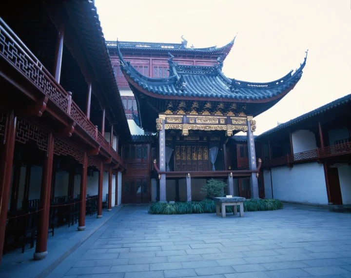 一座传统中式建筑围合的庭院中央矗立着装饰华丽的木结构门楼。
