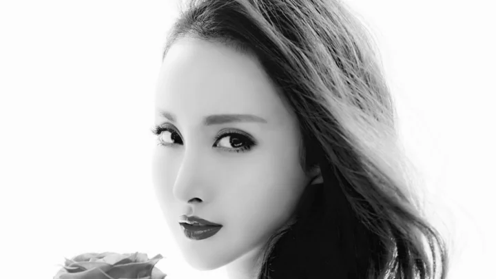 黑白画面中，一位成年女性以近距离侧面肖像呈现，左下角露出一朵玫瑰。