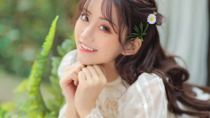 一位成年女性靠在窗边微笑，双手托腮，背景可见绿植。