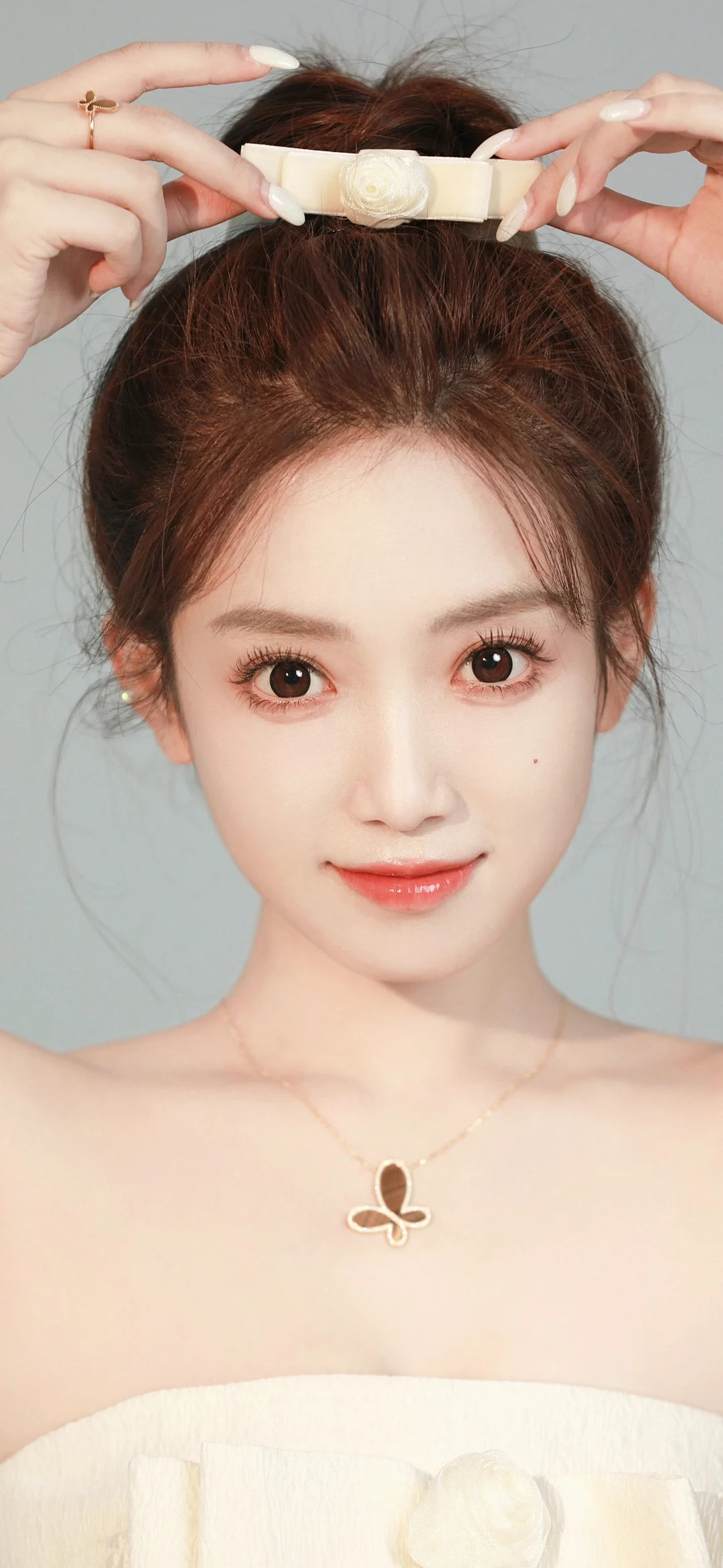 연한 회색 배경 앞에서 흰색 헤어밴드를 착용한 성인 여성이 카메라를 바라보고 있습니다.