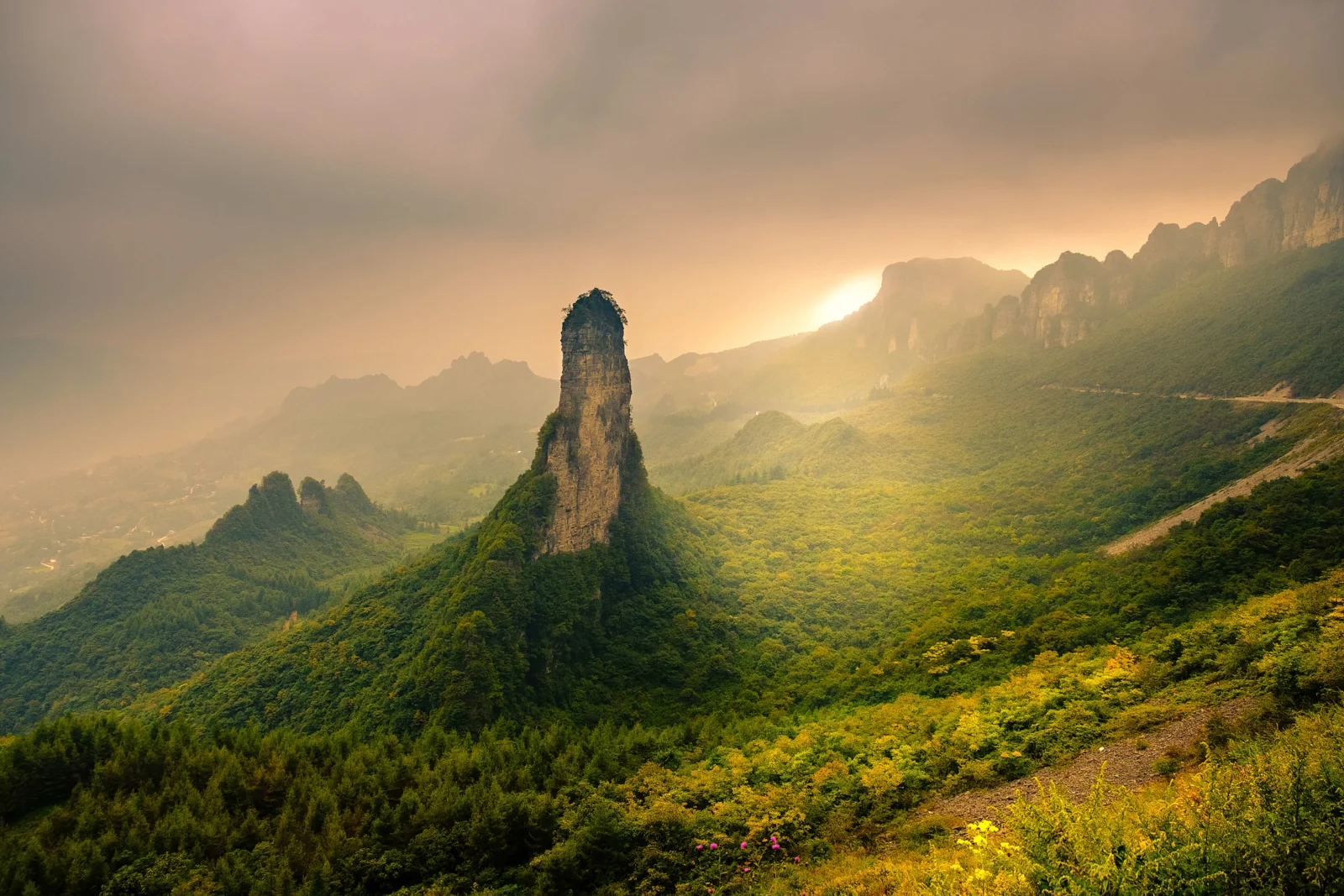 夕阳穿过云层照亮郁郁葱葱的恩施山谷与奇峰。