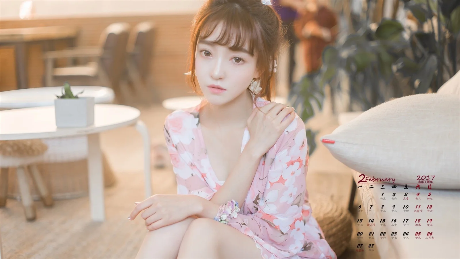 一名成年女性坐在室内空间中，身穿粉色花卉连衣裙，柔和光线映照着她的面容。