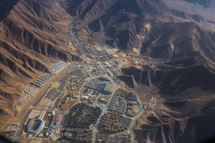 航拍展现了崎岖山脉环绕的山谷与密集建筑群。