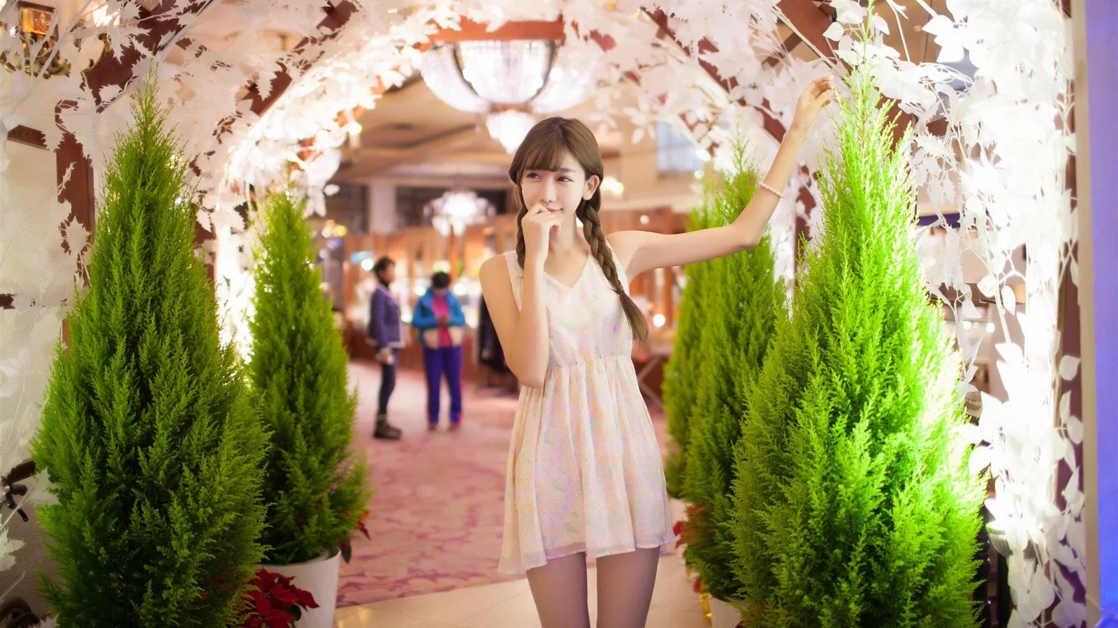 一名年轻女子站在室内花艺拱门与绿植之间。