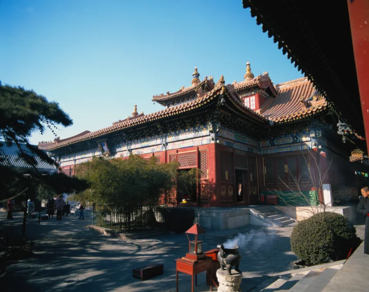 蓝天下，一座红墙金瓦的中国传统古建筑坐落在庭院中。