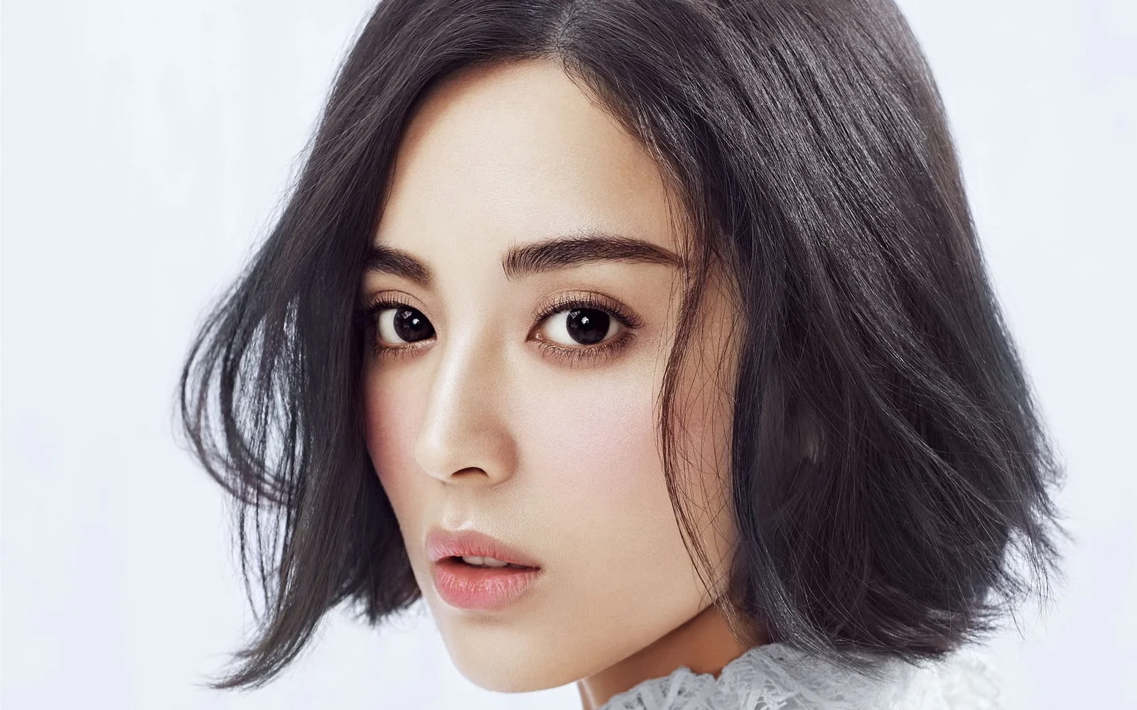 짙은 색의 짧은 머리를 한 성인 여성이 밝은 배경 앞에서 카메라를 바라보고 있습니다.