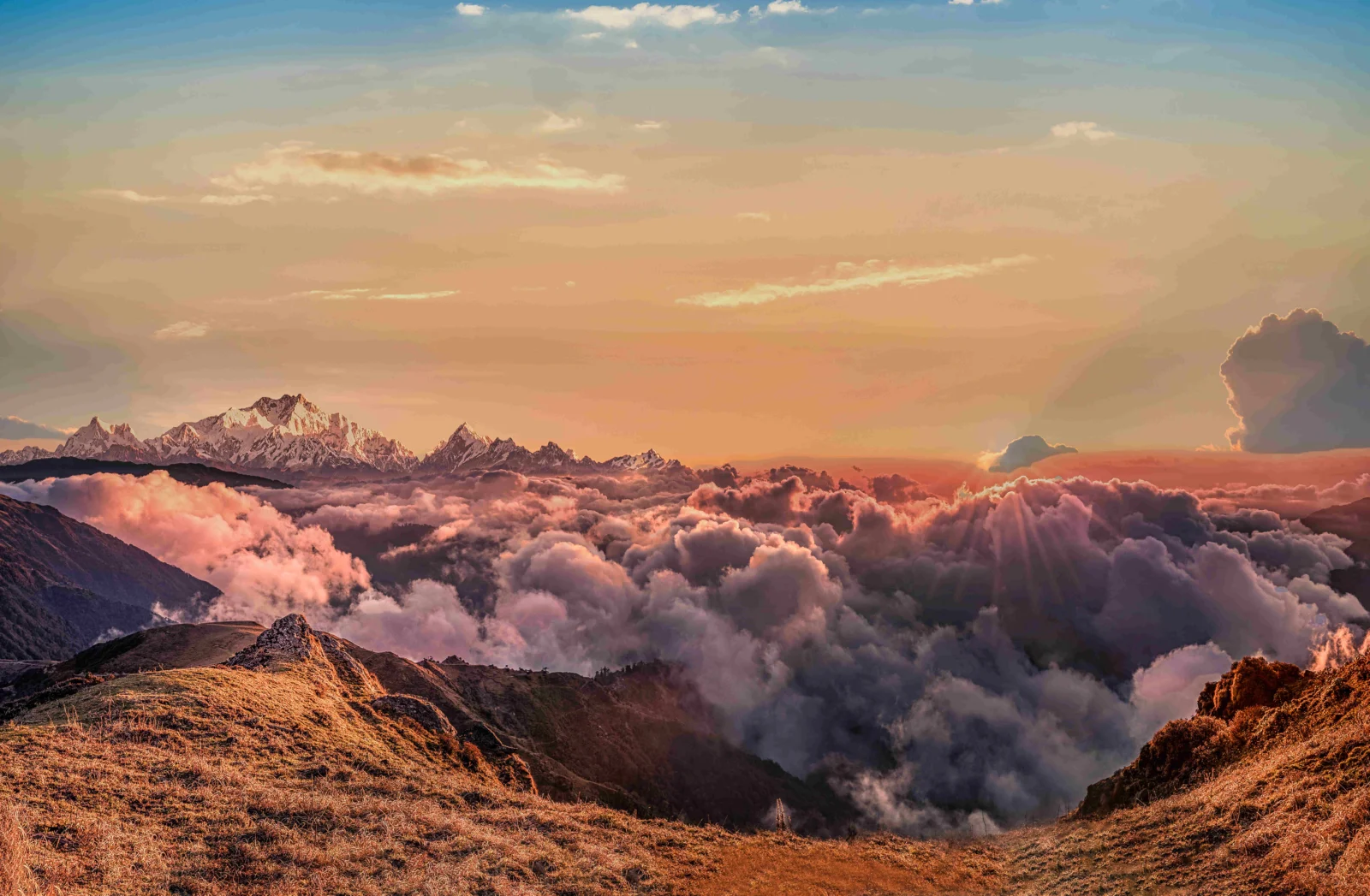 夕阳映照下，群山、云海与前景山坡构成壮丽的自然景观。