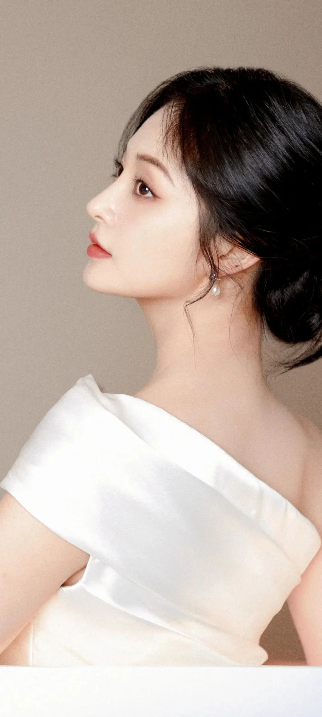 흰색 오프숄더 의상을 입은 성인 여성이 왼쪽을 향한 옆모습으로 보입니다.