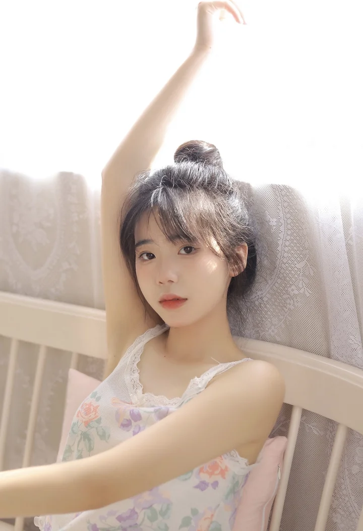 一名女性在室内靠坐，抬起一只手臂并面向镜头。
