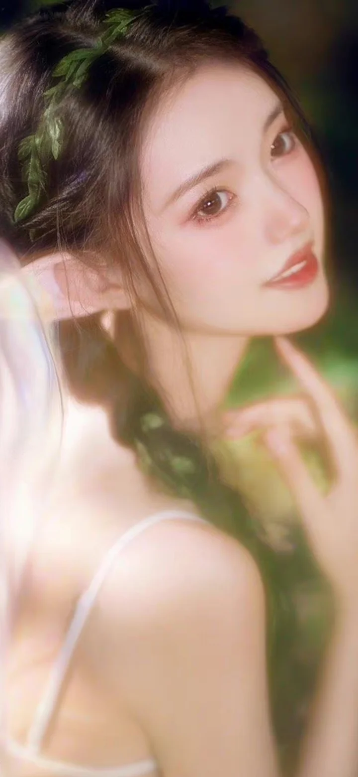 一位深色长发女性在柔和光线下回眸看向镜头，背景呈现朦胧的绿色光影。