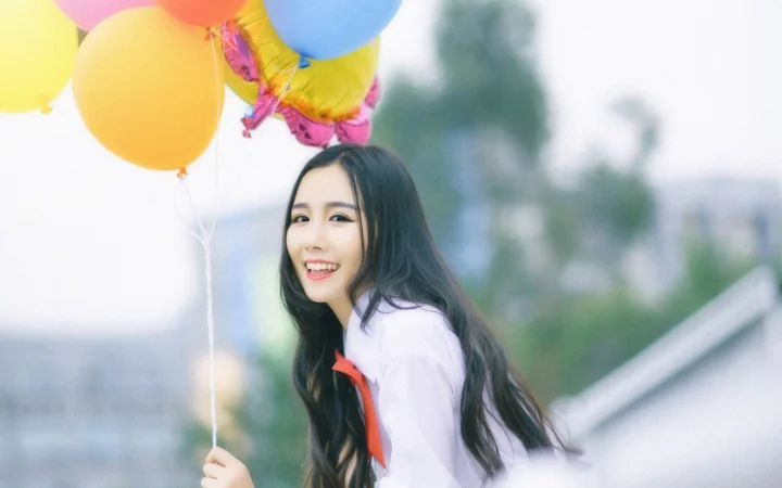一名長髮女子在戶外氣球旁微笑面對鏡頭。