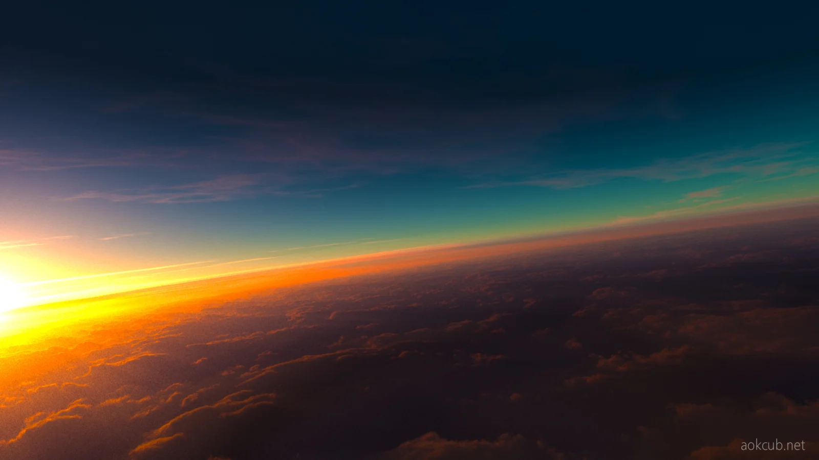夕阳从云层上方照亮倾斜的地平线，天空呈现深蓝、青绿与橙黄色渐变。