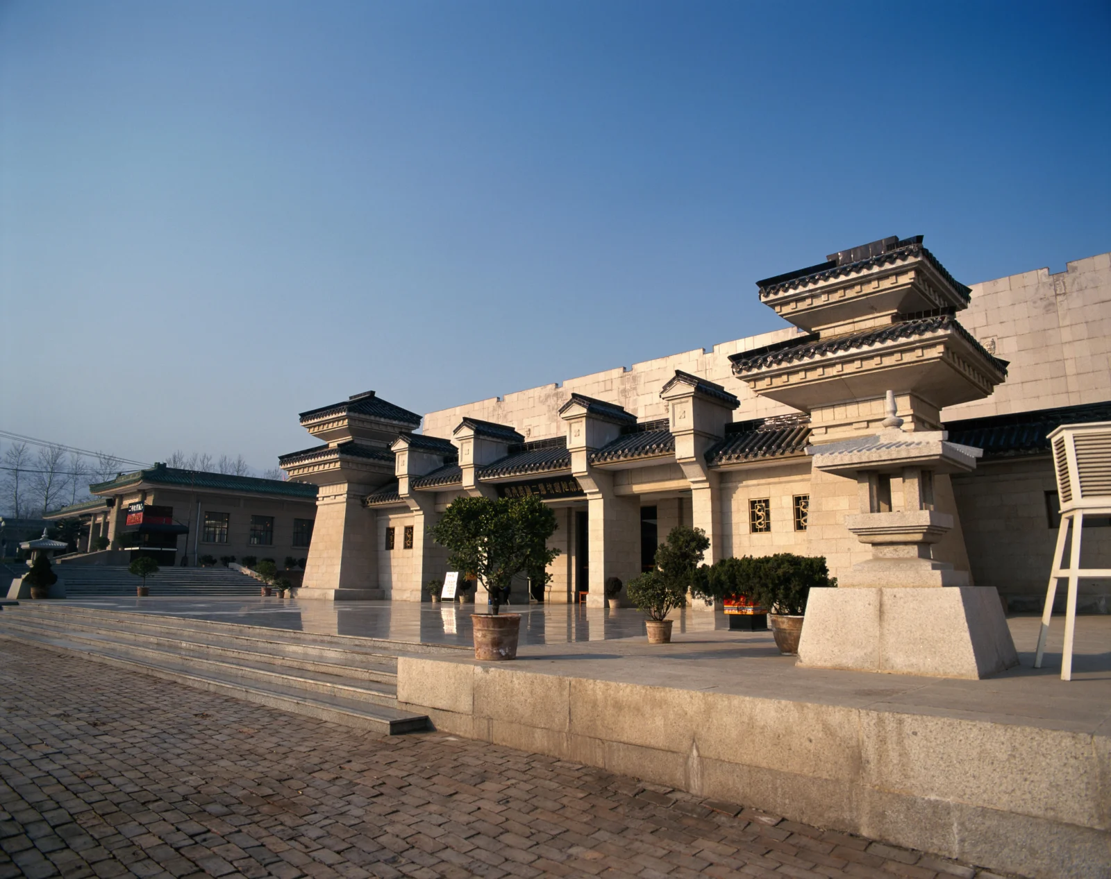 阳光下的中式古建筑庭院展现出石材建筑、层叠屋檐和开阔台阶。