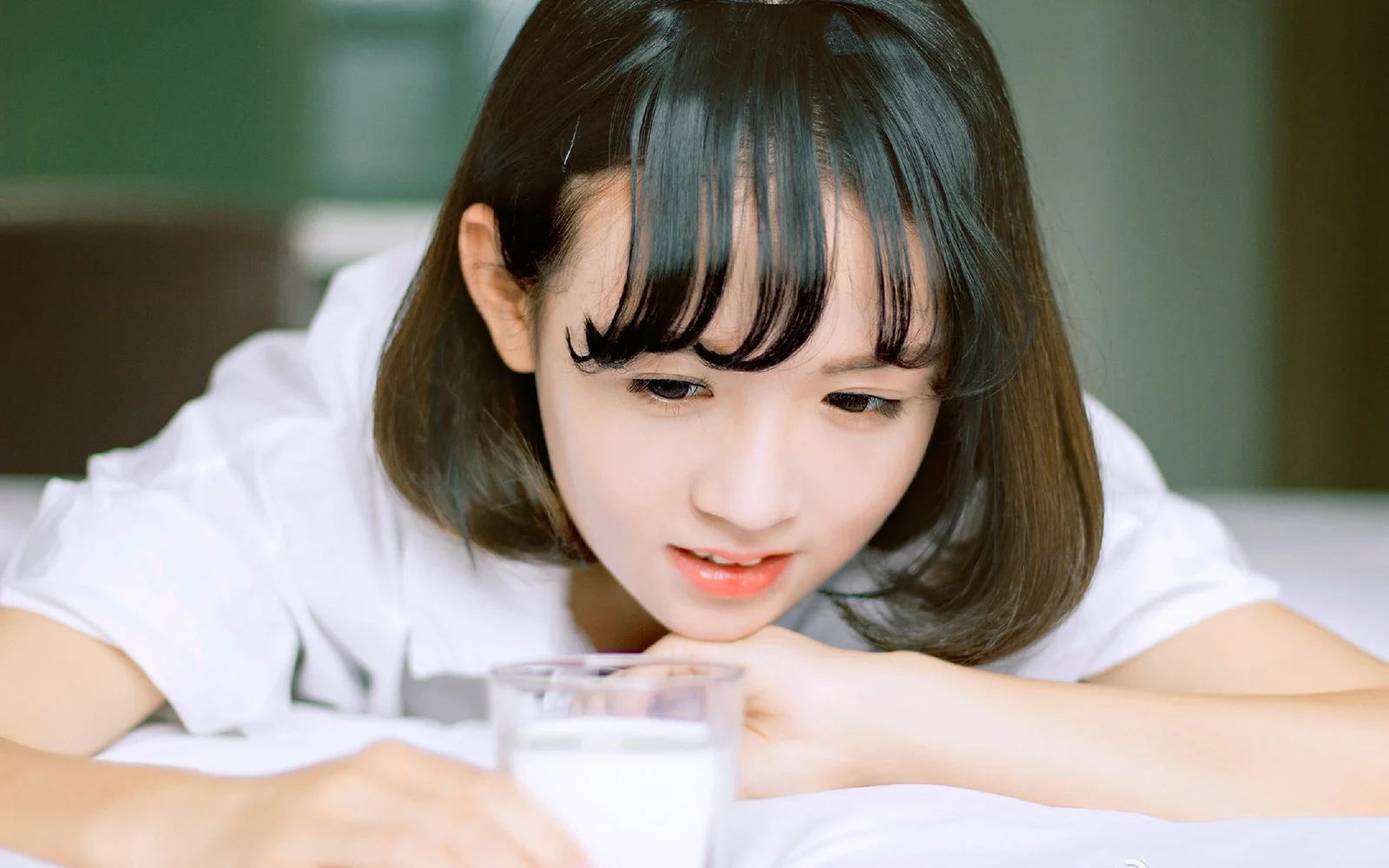 一名女性俯身看著桌前的一杯牛奶。