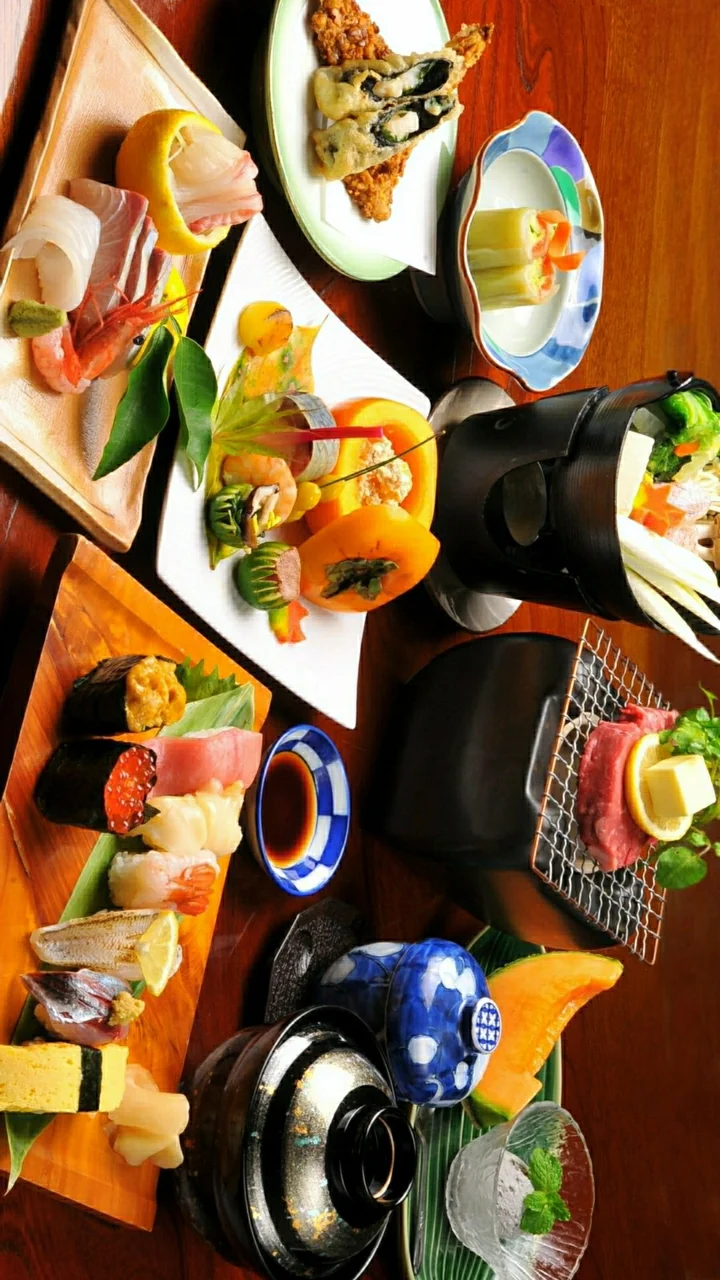 木桌上摆放着多盘寿司、日式料理、酱油和餐具。