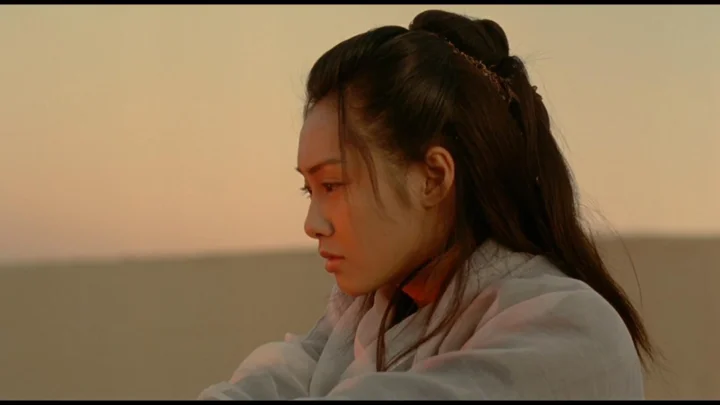 一名长发女性身穿浅色衣物，在温暖的夕阳背景前呈侧面轮廓。