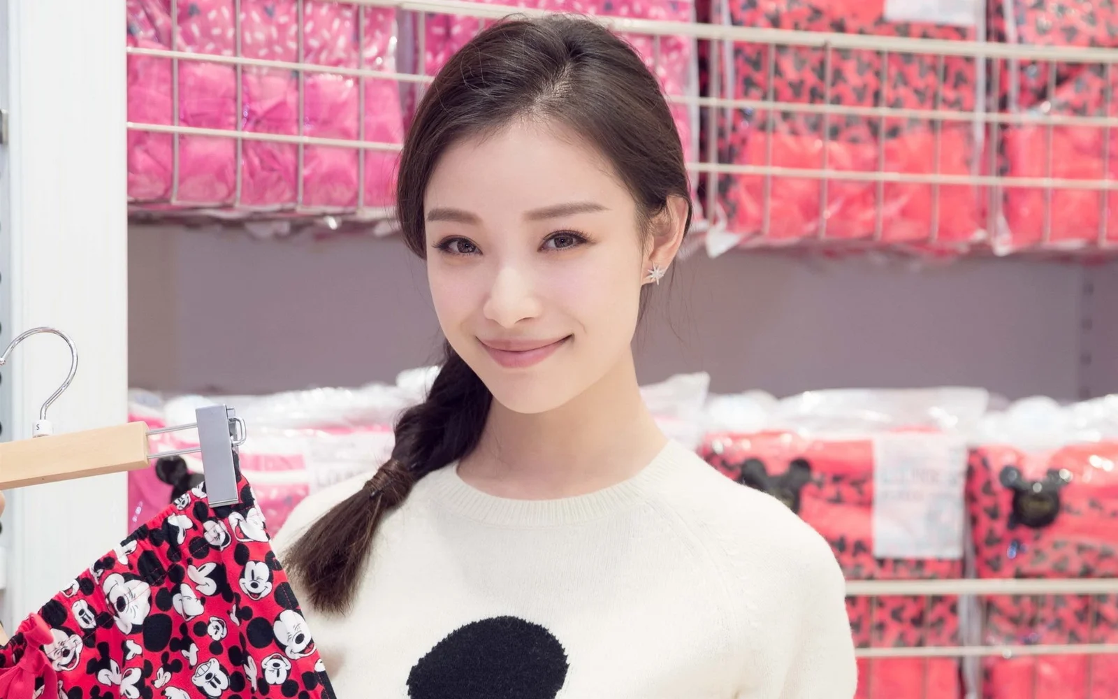 一位扎着侧编发的年轻女性在室内微笑面对镜头。