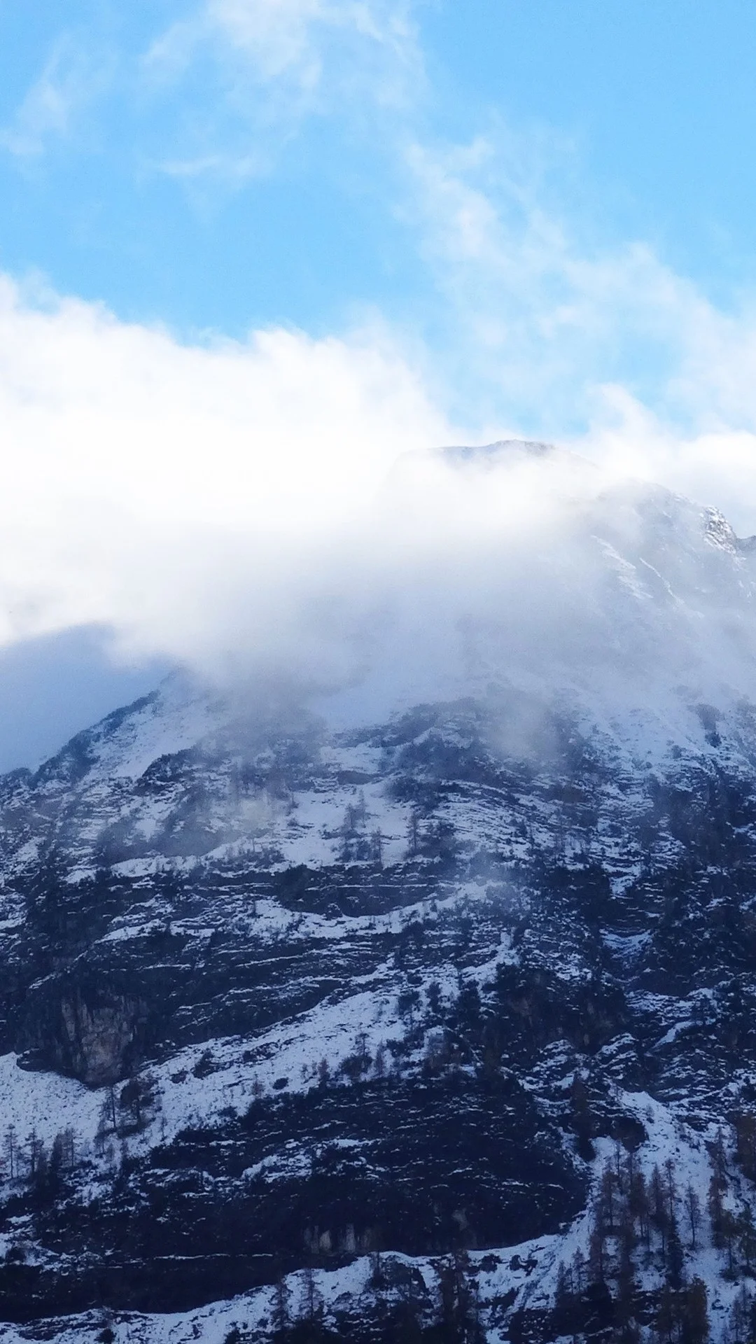 云雾缭绕的积雪山峰在蓝天下延展开来。