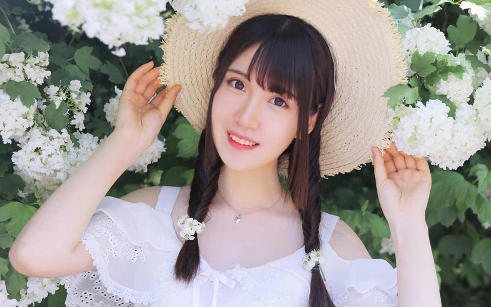 一位戴着草帽、扎着双辫的女性站在白色花朵之间。
