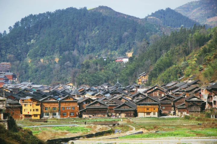 群山环绕的传统木屋村落坐落在田野与溪流之间。