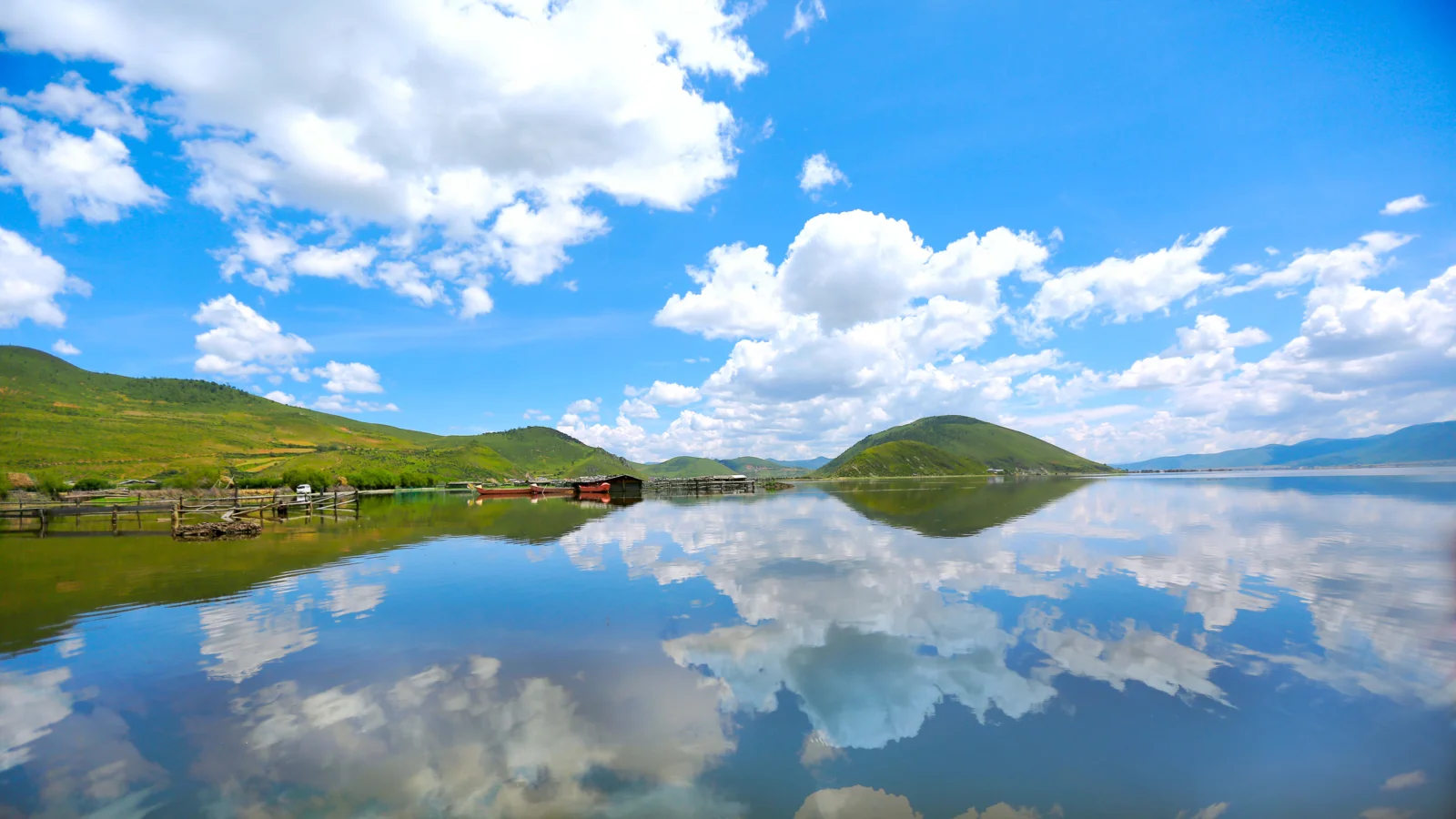 湖面倒映着蓝天白云与青山，构成开阔宁静的自然风景。