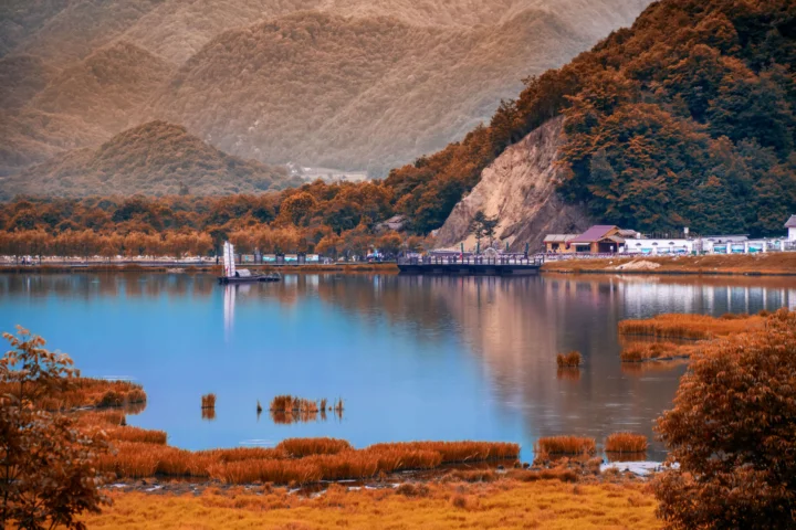 湖水倒映着群山、森林和湖岸的金色芦苇。