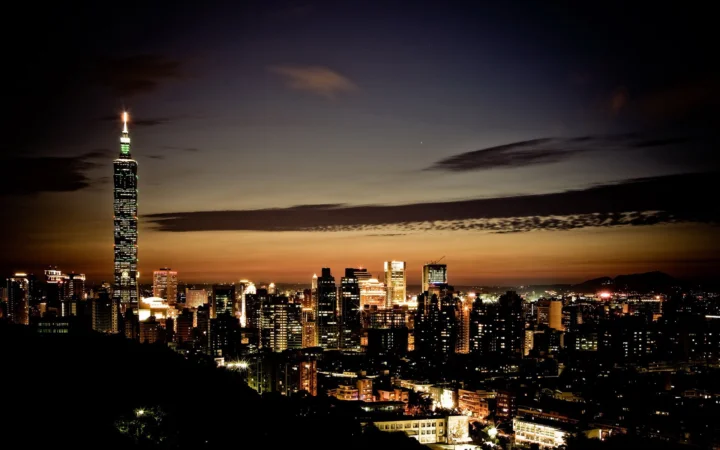 暮色中的城市天际线灯火通明，高耸建筑与台北101映衬在深色天空下。