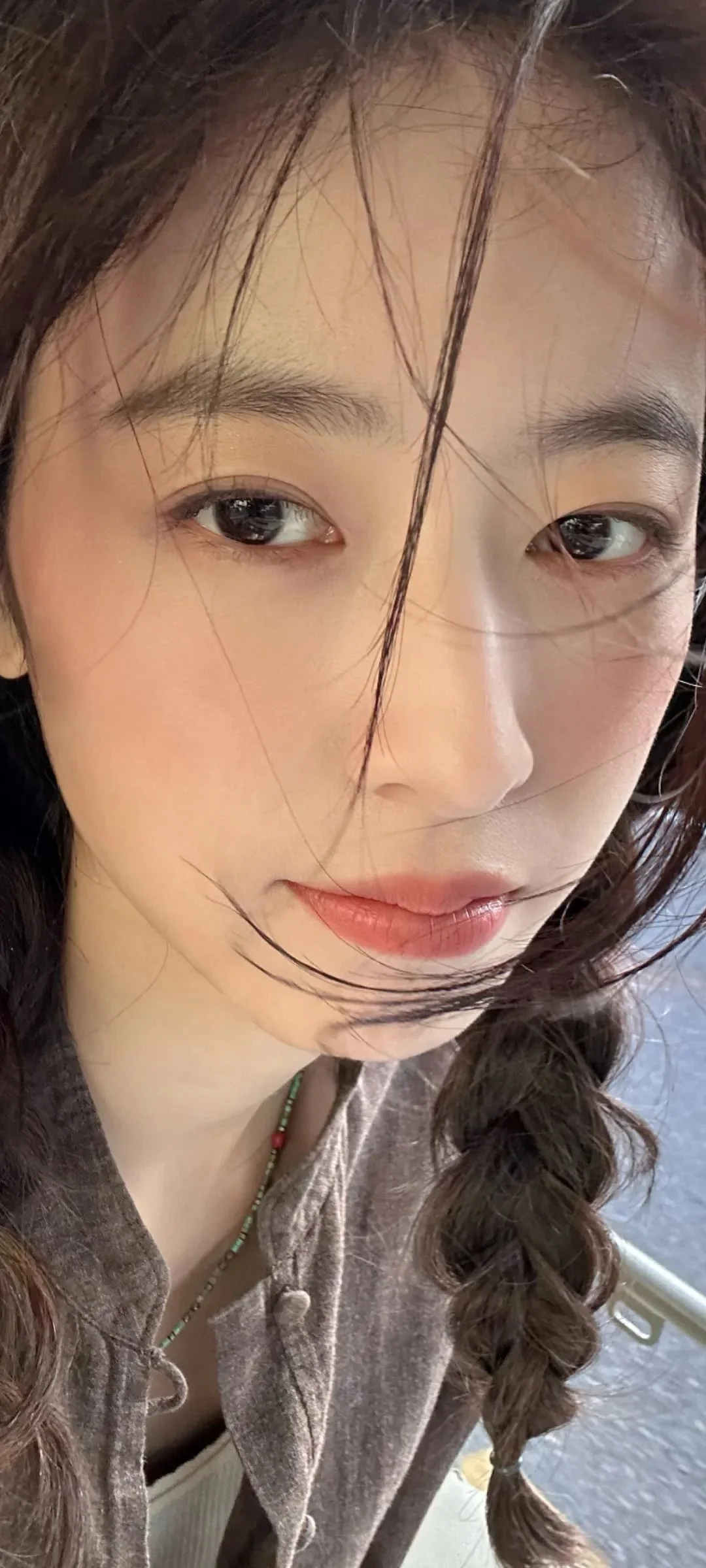 긴 머리를 땋은 성인 여성의 얼굴을 화면 대부분에 담은 클로즈업 초상입니다.