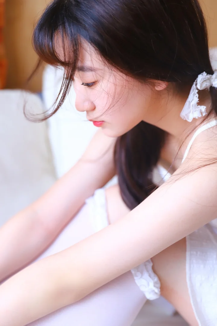 一名黑发女性在室内柔和光线下低头侧望。