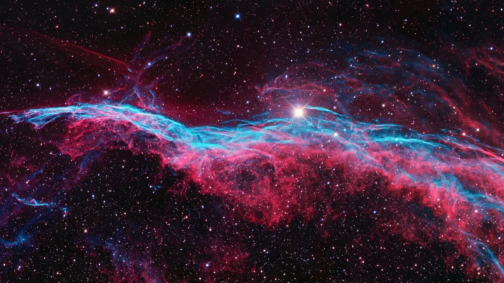 画面展示了深色星空中交织的蓝红色发光星云与密集星点。