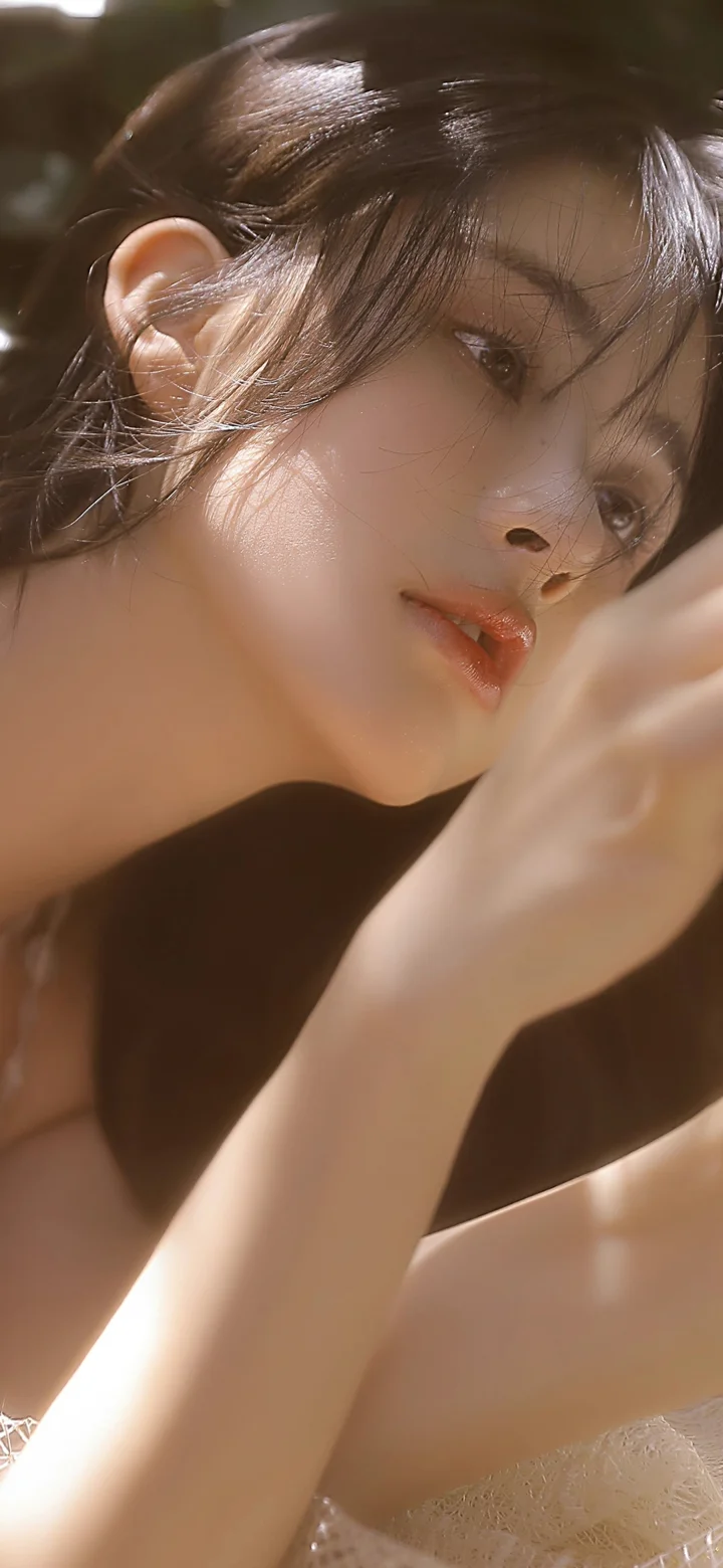一位棕色头发的女性在暖色光线下侧脸凝视镜头，画面为近距离人像构图。