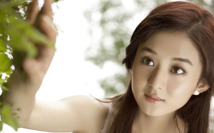 一位成年女性在绿叶间抬头凝望。